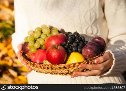 Woman's hands holding a basket with fresh fruit. Close-up