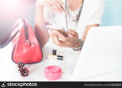 Woman's hands holding mobile phone and using laptop. Online shopping