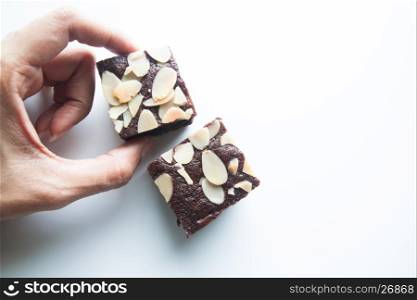 Woman's hands picks chocolate brownie isolated on white background