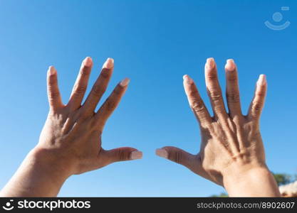 woman’s hands showing all ten fingers on a blue sky background,. Toma de manos de mujer joven aisladas sobre fondo azul