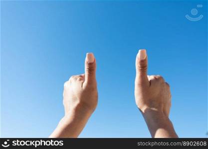 woman’s hands showing thumbs on a blue sky background,. woman’s hand showing thumbs up with blue sky background