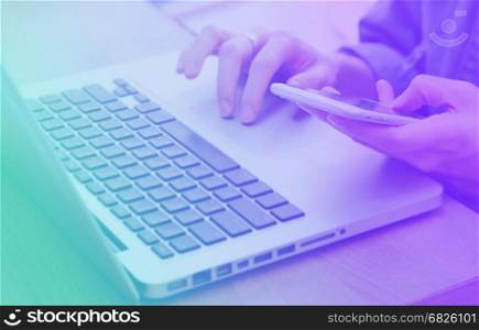 Woman's hands using smartphone and laptop in workplace or home, business and technology concept, color transitions style