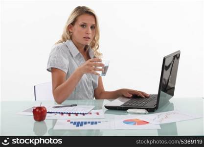 Woman sat at desk drinking