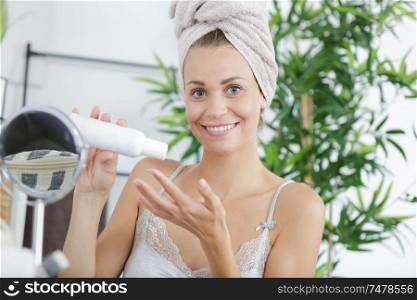 woman sat at mirror applying skincare product