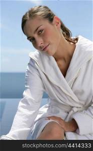 Woman sat at the seaside in white robe