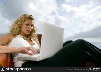 Woman sat at the seaside with laptop