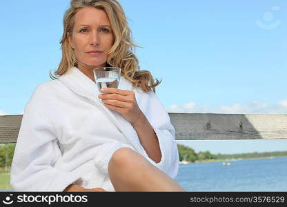 Woman sat by lake in bath robe