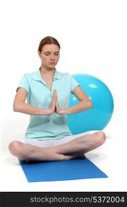 Woman sat in yoga position by exercise ball