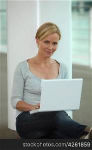 Woman sat next to column using laptop computer