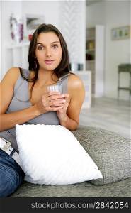 Woman sat on sofa with glass of water