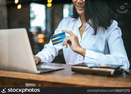 woman sat with a laptop and paid with a credit card in a coffee shop.