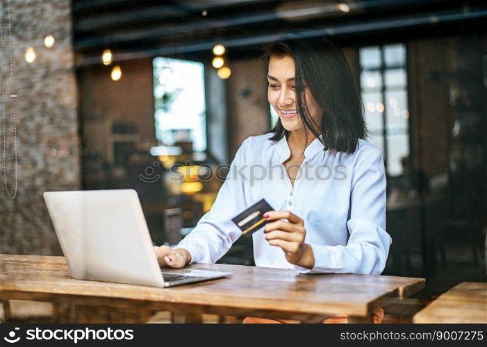 woman sat with a laptop and paid with a credit card in a coffee shop.