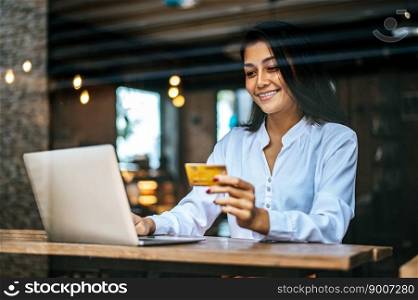 woman sat with a laptop and paid with a credit card in a coffee shop.