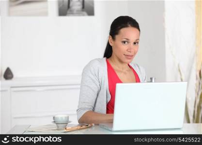 Woman sat with cup of coffee by laptop