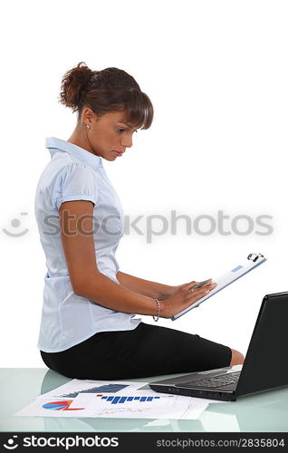 Woman sat with laptop and clip-board