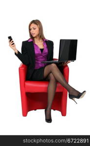 Woman sat with mobile telephone and computer