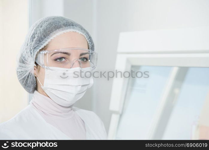 Woman scientist in a white protective clothing preparing for the experiments in the laboratory