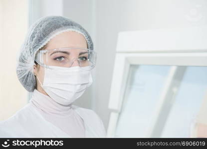 Woman scientist in a white protective clothing preparing for the experiments in the laboratory