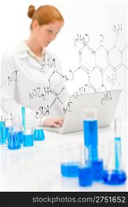 Woman scientist in laboratory with laptop and chemical formula