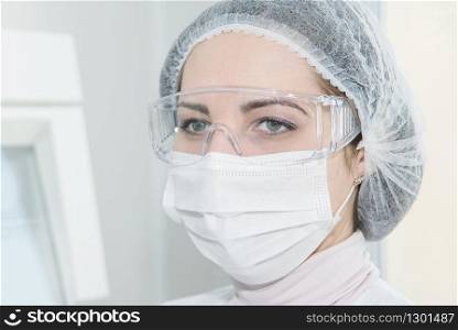 Woman scientist or a doctor in a white protective clothing in the laboratory, close-up portrait