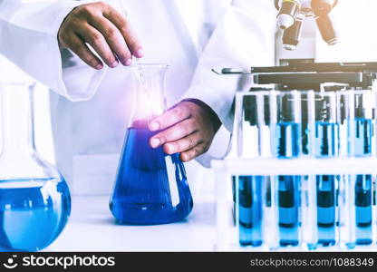 Woman scientist working in laboratory and examining biochemistry sample in test tube. Science technology research and development study concept.