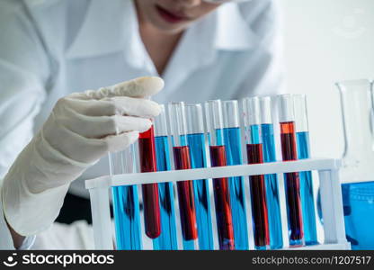 Woman scientist working in laboratory and examining biochemistry sample in test tube. Science technology research and development study concept.