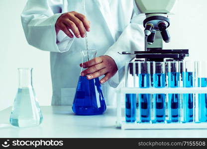 Woman scientist working in laboratory and examining biochemistry sample in test tube. Science technology research and development study concept.