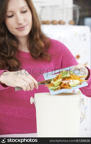 Woman Scraping Vegetable Peelings Into Recycling Bin