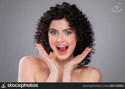 Woman screaming amazed in joy. Surprised excited beautiful woman screaming amazed in joy, gray background