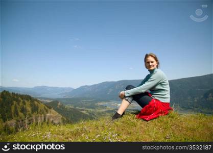 Woman seats at the top of a cliff relaxing