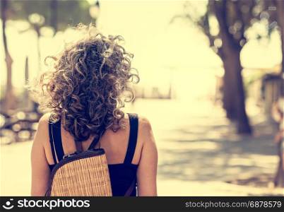 Woman seen from behind. Walking on a path toward an uncertain future but bright. Conceptual image.