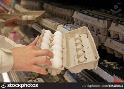 Woman selecting egg in grocery store produce department. Coquitlam, BC, Canada - May 02, 2017 : Woman selecting egg in grocery store produce department