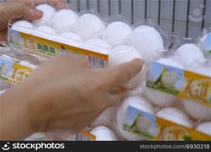 Woman selecting egg in grocery store produce department. Taipei, Taiwan - October 19, 2017 : Woman selecting egg in grocery store produce department
