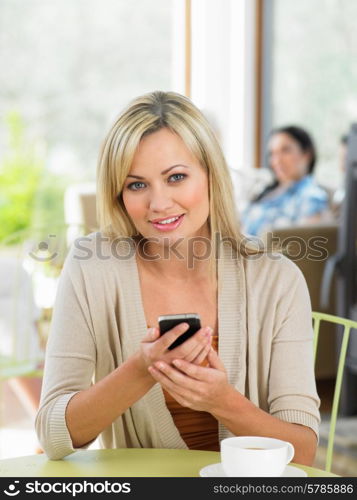 Woman Sending Text Message In Cafe