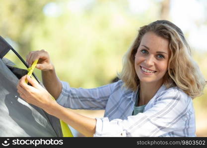 woman setting up a tent and smiling at the camera