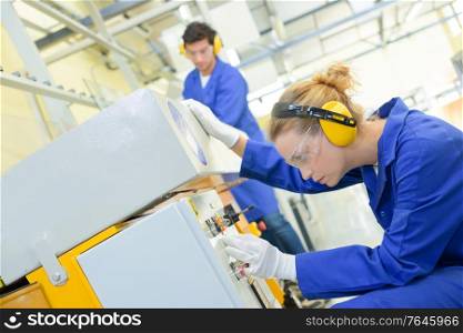 Woman setting up machine in factory