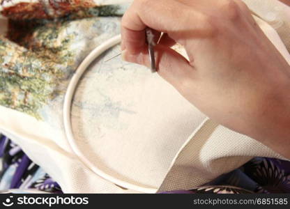 Woman sewing decoration picture on the white fabric