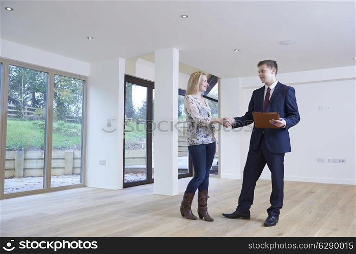 Woman Shaking Hands With Estate Agent In New Home