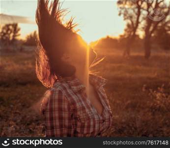 Woman shaking her head in sunset light