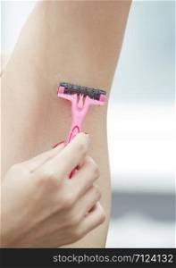 Woman shaving armpit. Close-up vertical photo