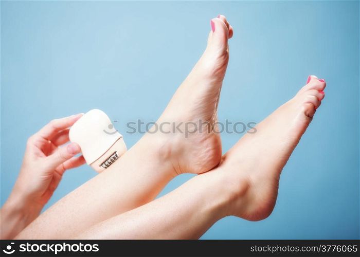 woman shaving her legs with electric shaver depilation on blue. Beauty and body skin care concept.