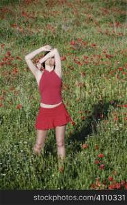 Woman shields eyes from sunlight in field of wildflowers, Granada, Andalusia
