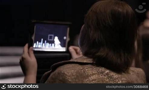 Woman shooting performance on the stage with touchpad. Back view.
