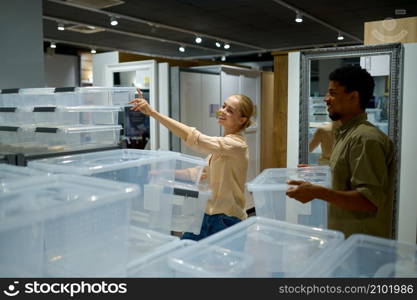 Woman shopper choosing plastic storage containers in household goods store. Shopping and retail. Woman shopper choosing plastic containers in store