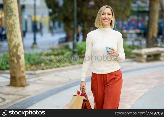 Woman shopping and carrying shopping bags and a coffee in a to-go glass.. Woman shopping and carrying shopping bags and a coffee in a to-go cup.