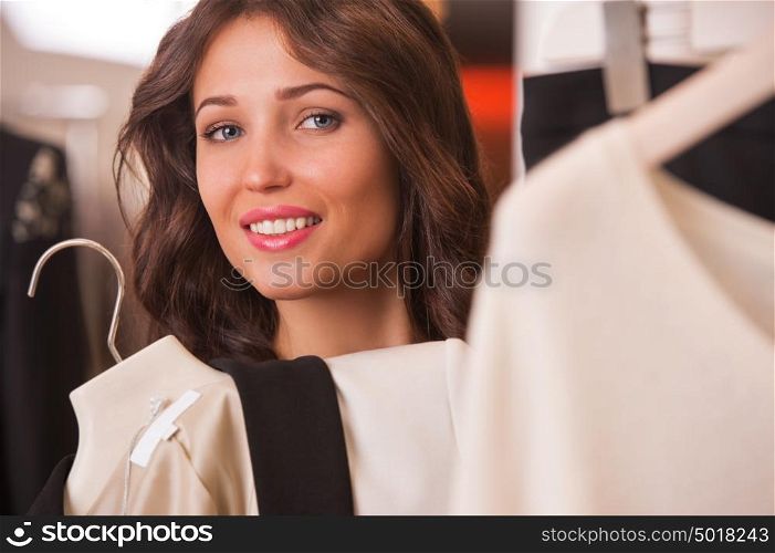Woman shopping choosing dresses. Beautiful young shopper in clothing store.