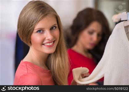 Woman shopping clothes. Shopper looking at camera indoors in store. Beautiful happy smiling caucasian female model.