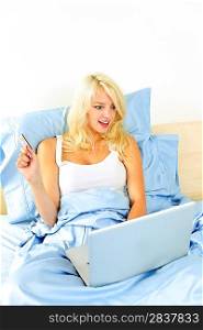 Woman shopping in bed with computer
