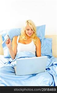 Woman shopping online in bed with computer