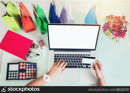 Woman shopping online using laptop blank screen with credit card enjoying in home